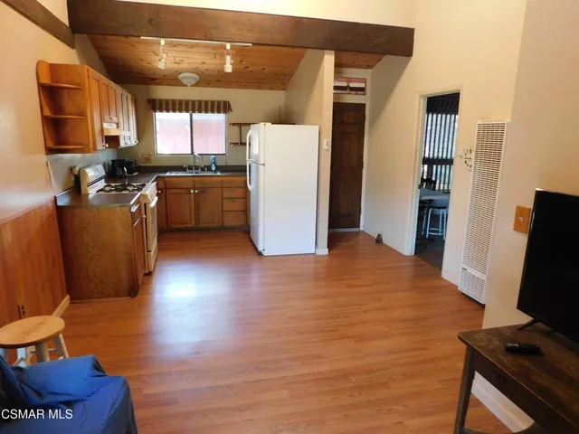 a kitchen with a refrigerator wooden floor and a view of living room