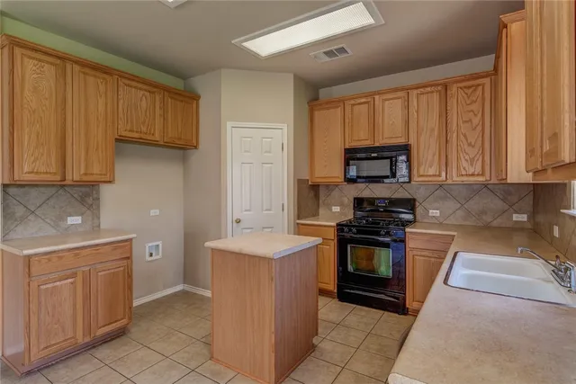a kitchen with stainless steel appliances granite countertop a stove a sink and a microwave