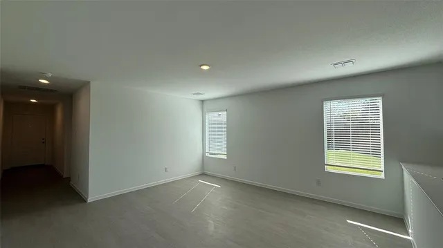 a large white kitchen with stainless steel appliances granite countertop a stove a sink a refrigerator and white cabinets with wooden floor