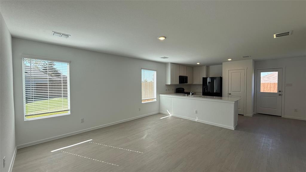 7701 Rutherford Lane McKinney, TX 75069 - Photo 8 of 20 a large white kitchen with stainless steel appliances granite countertop a stove a sink a refrigerator and white cabinets with wooden floor