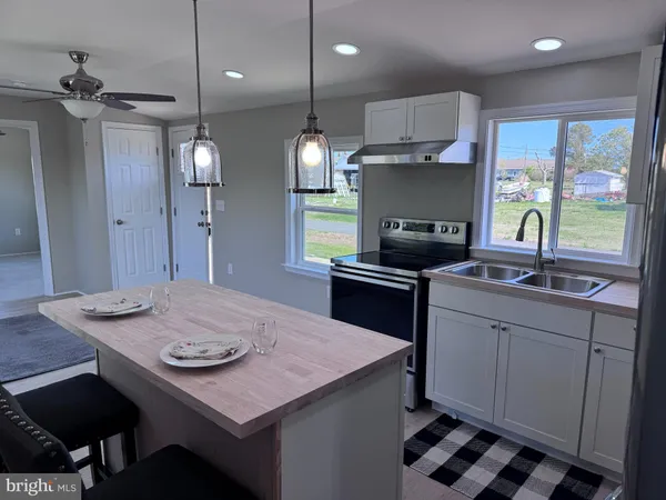 a kitchen with stainless steel appliances kitchen island granite countertop a table chairs cabinets and wooden floor