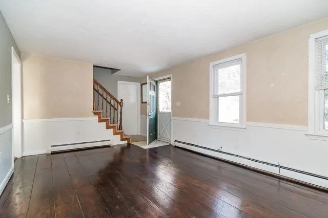 an empty room with wooden floor fireplace and windows