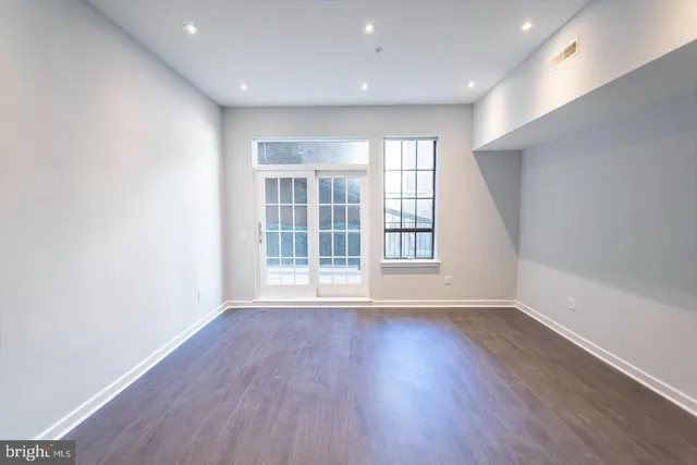 an empty room with wooden floor and windows