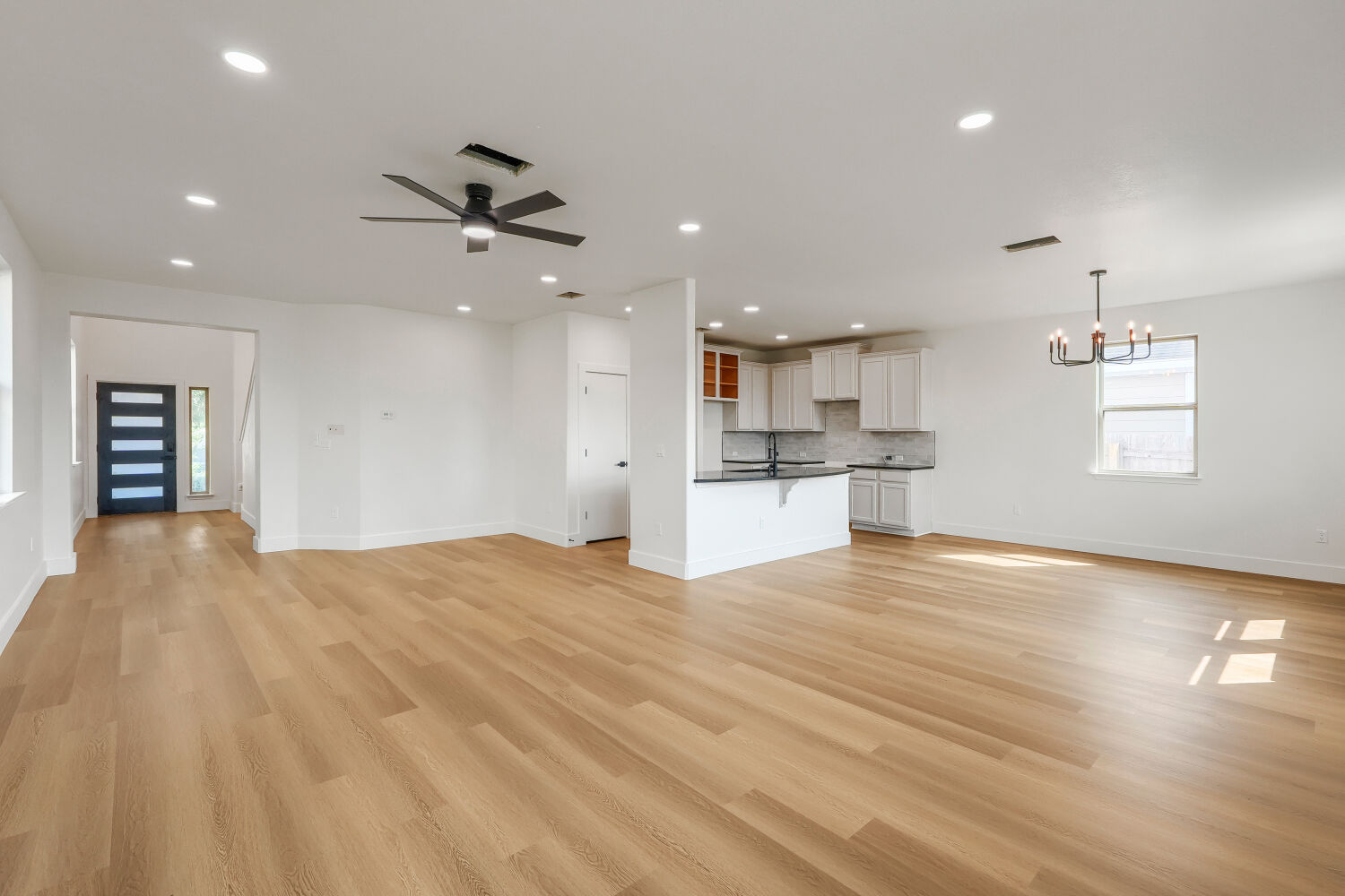 320 Triumph Road Buda, TX 78610 - Photo 2 of 22 Warm wood flooring flows seamlessly through this airy, open-concept main level living area.