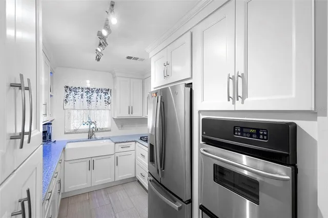 a kitchen with granite countertop a sink dishwasher a stove and a microwave oven with cabinets