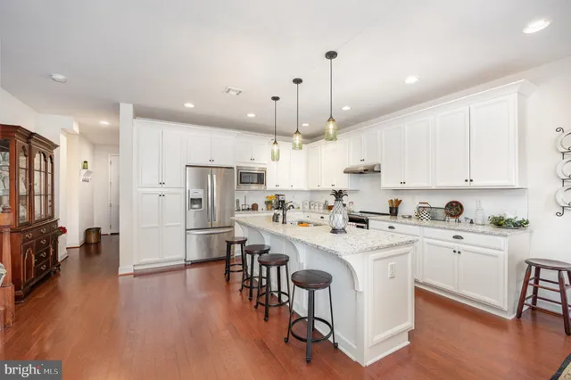 a kitchen with stainless steel appliances kitchen island wooden floors and white cabinets