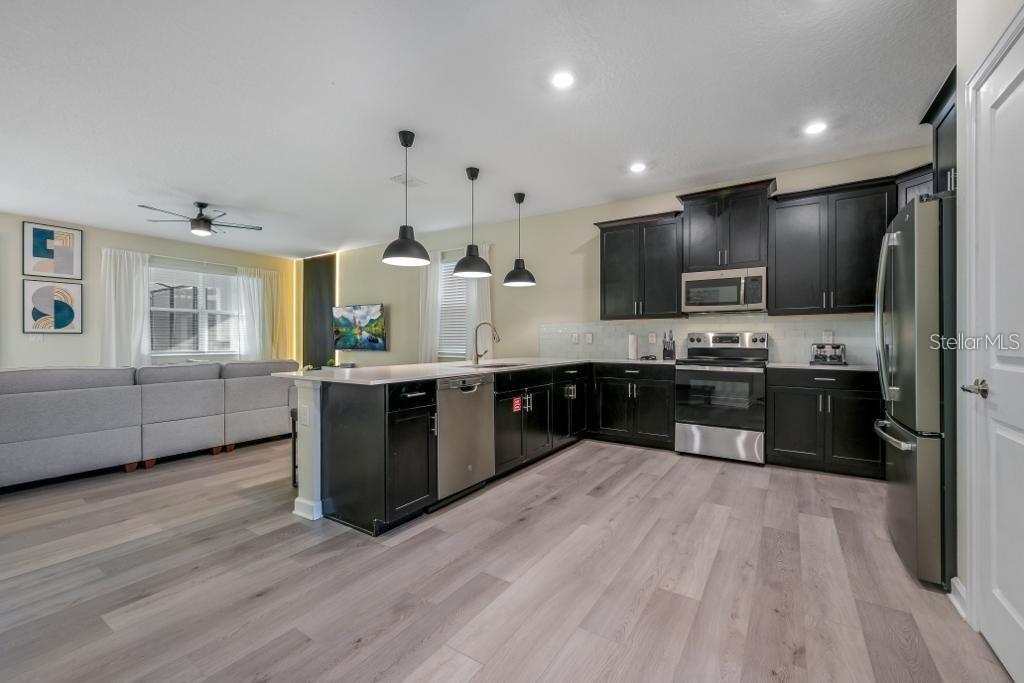 4532 Target Boulevard Kissimmee, FL 34746 - Photo 27 of 52 a large kitchen with stainless steel appliances kitchen island granite countertop a stove a sink dishwasher a refrigerator and white cabinets with wooden floor