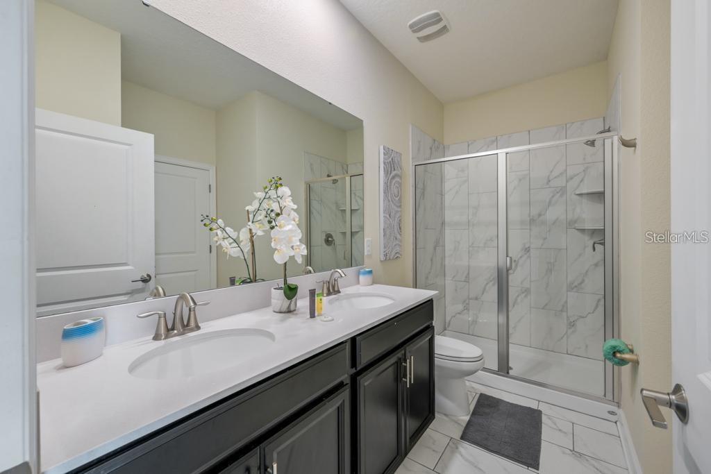 4532 Target Boulevard Kissimmee, FL 34746 - Photo 41 of 52 a bathroom with a double vanity sink a toilet and a mirror