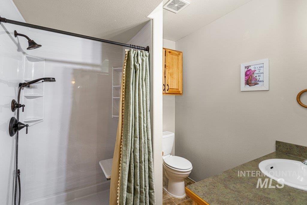 1028 Granlund Road Troy, ID 83871 - Photo 36 of 46 Shower with multiple spray functions and built-in shelving, complemented by a vanity with an integrated sink, and an overhead wooden cabinet