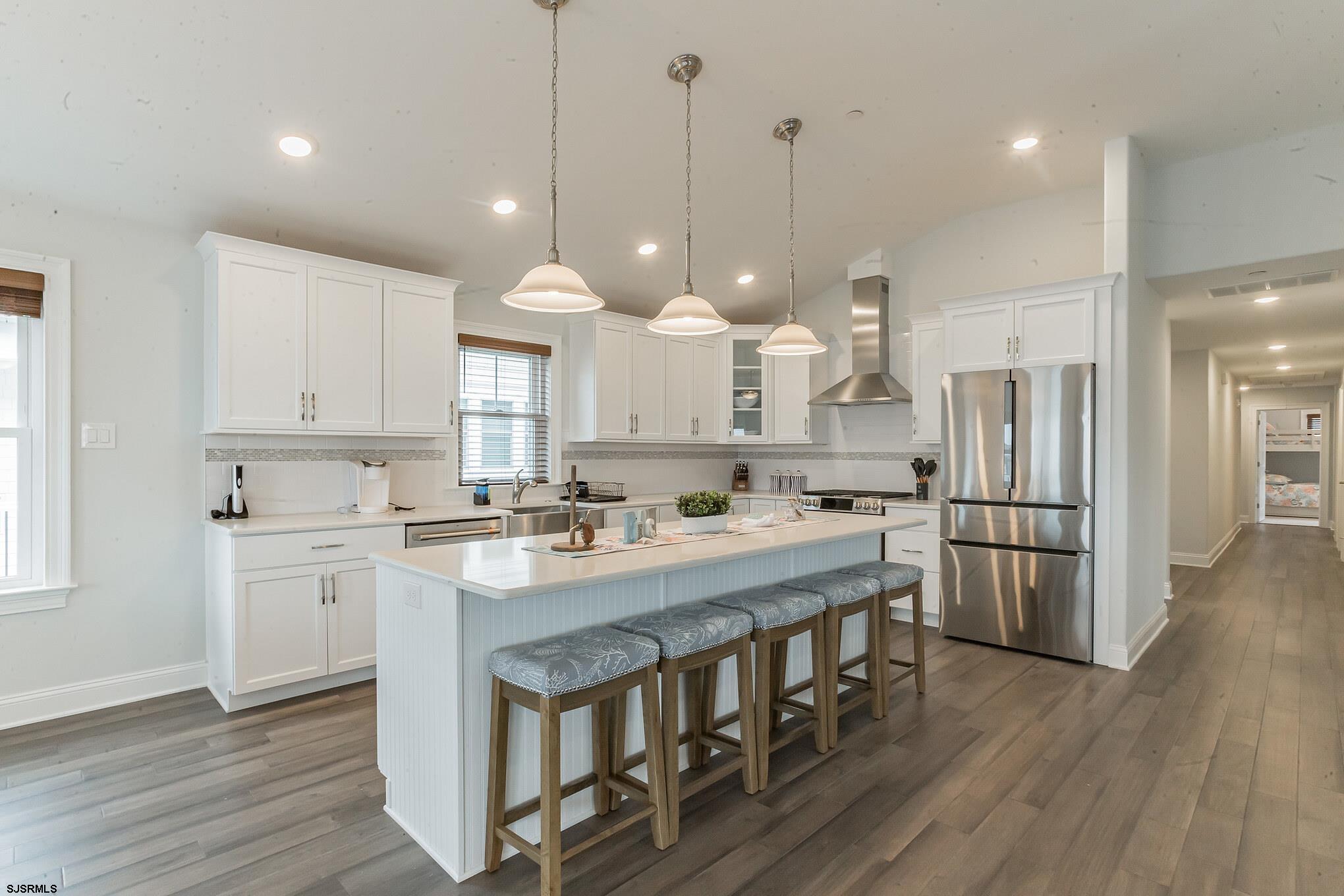 910 Ocean Avenue, Unit C Ocean City, NJ 08226 - Photo 11 of 30 a large kitchen with kitchen island a stove a sink a refrigerator and white cabinets with wooden floor