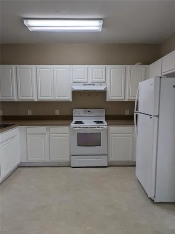 a kitchen with white cabinets and white appliances
