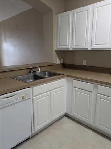 a kitchen with white cabinets and sink