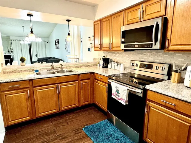 a kitchen with stainless steel appliances granite countertop a sink a stove top oven and wooden floors