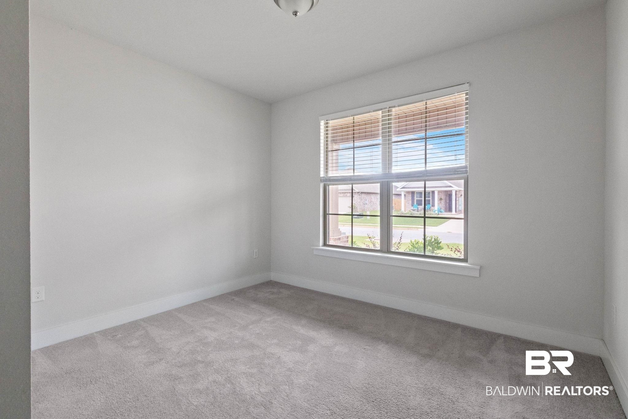 1710 Grouse Street Foley, AL 36535 - Photo 53 of 76 Bright room featuring a prominent window with horizontal blinds, neutral carpeting, white baseboards, and a flush mount ceiling light fixture