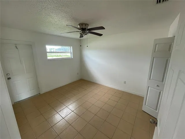 an empty room with a ceiling fan and window