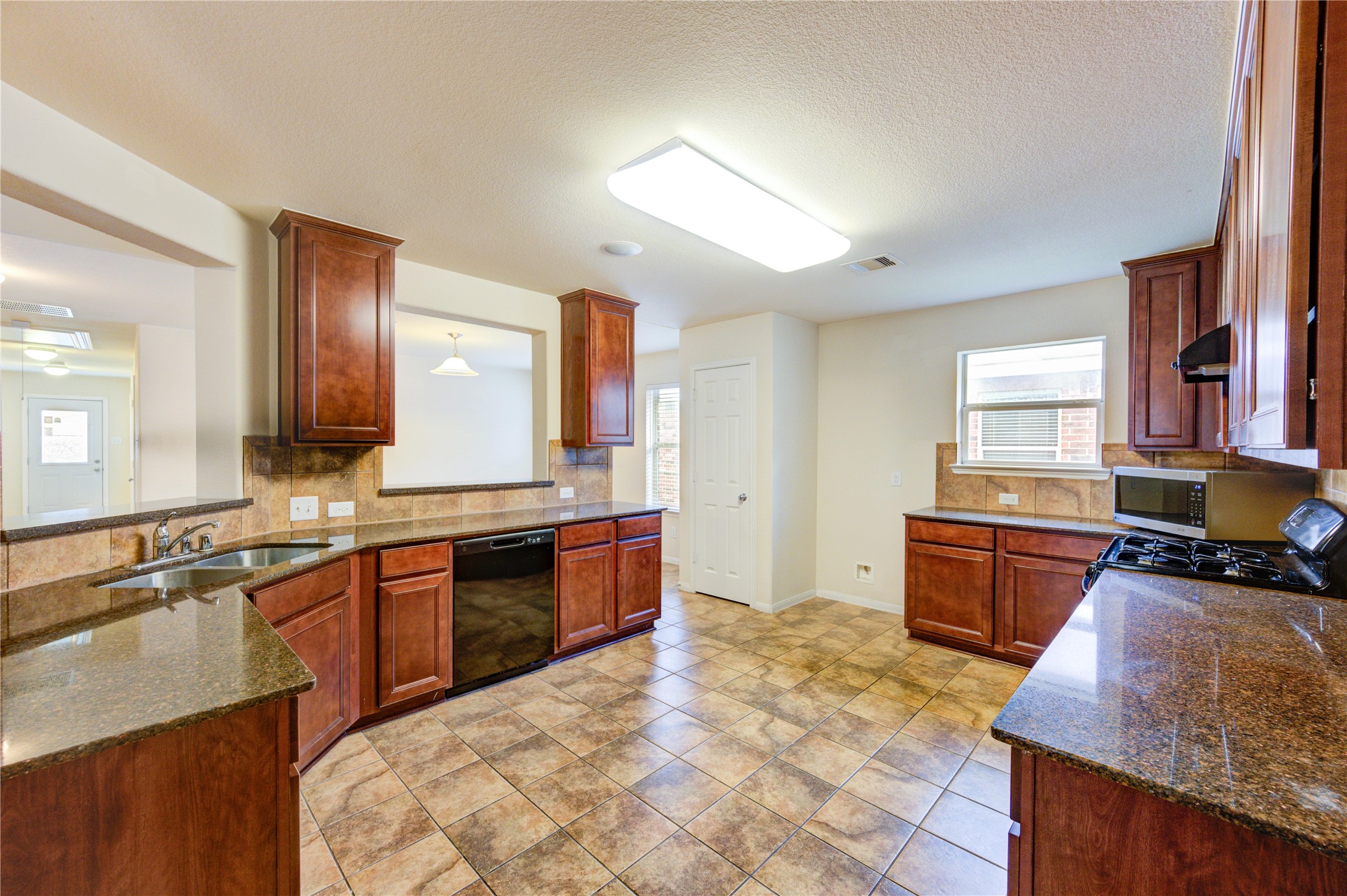 2922 Halcyon Time Trail Houston, TX 77045 - Photo 32 of 50 a large kitchen with a stove a sink dishwasher a oven with wooden cabinets and floor
