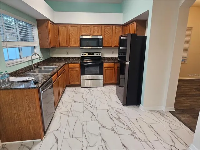 a kitchen with stainless steel appliances granite countertop a refrigerator stove and sink
