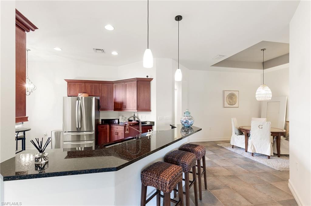 7563 Moorgate Point Way Naples, FL 34113 - Photo 17 of 40 a kitchen with stainless steel appliances granite countertop a sink counter space and living room view