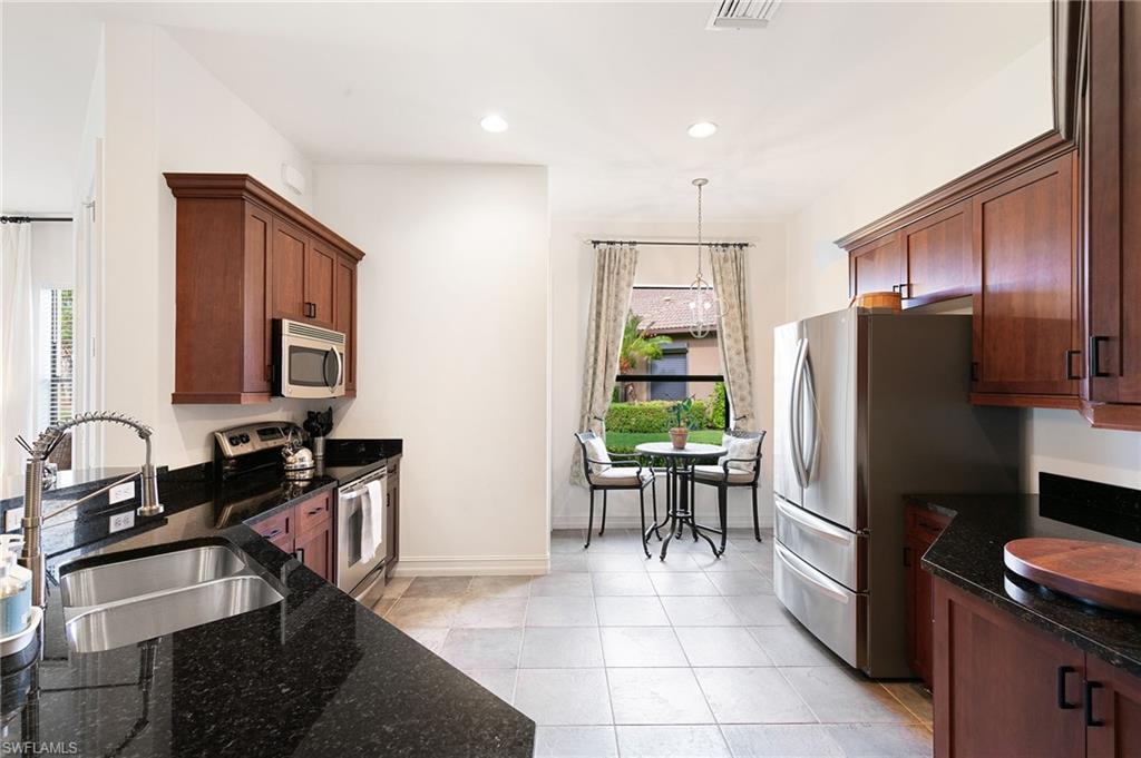 7563 Moorgate Point Way Naples, FL 34113 - Photo 19 of 40 a kitchen with kitchen island granite countertop a refrigerator stove microwave and sink