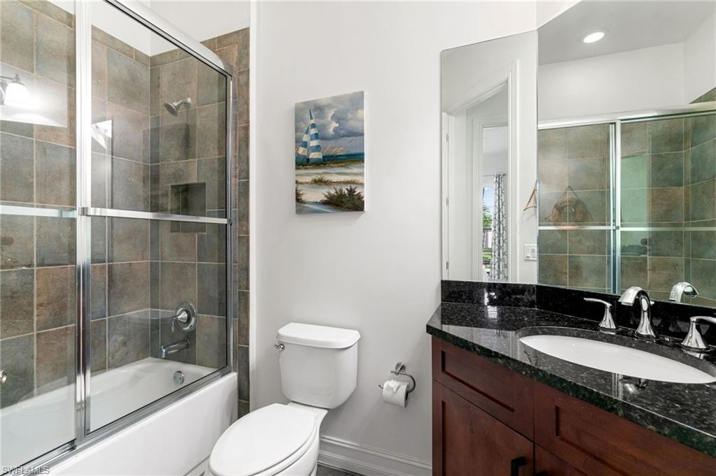 7563 Moorgate Point Way Naples, FL 34113 - Photo 26 of 40 a bathroom with a granite countertop sink a toilet a mirror and shower
