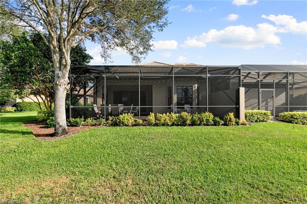 7563 Moorgate Point Way Naples, FL 34113 - Photo 10 of 40 a view of a backyard with table and chairs and a large tree