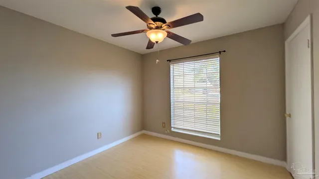 a view of an empty room with window and a ceiling fan