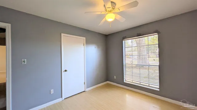 an empty room with windows and fan