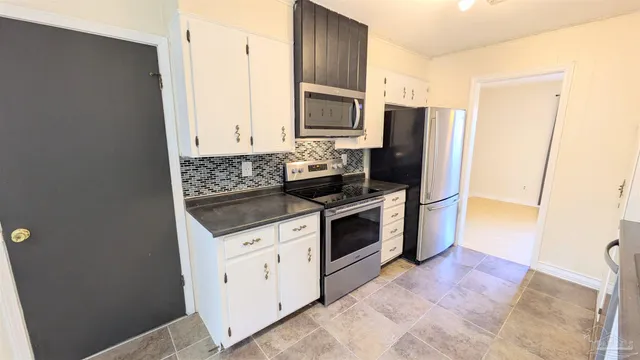 a kitchen with stainless steel appliances a stove a microwave a refrigerator a sink and dishwasher with wooden floor