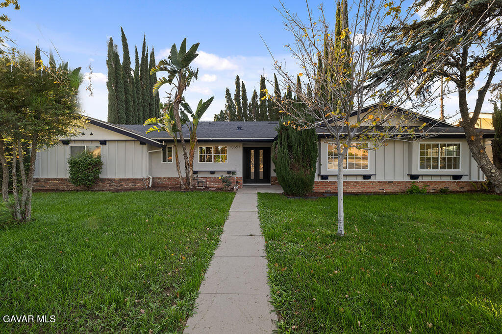 a front view of a house with a garden and trees