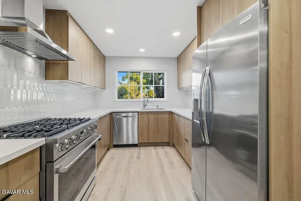 a kitchen with stainless steel appliances granite countertop a stove a sink and a refrigerator