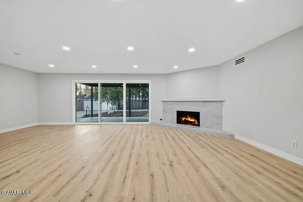 a view of an empty room with wooden floor and a fireplace