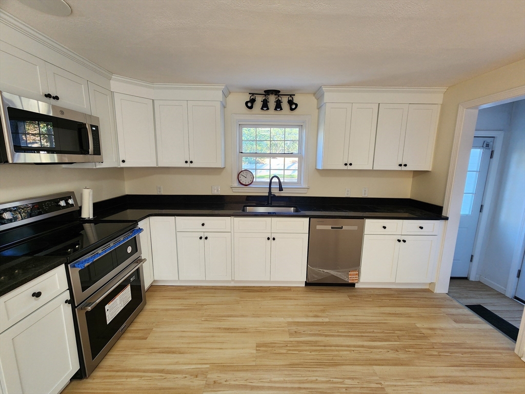 236 Pondview Drive Springfield, MA 01118 - Photo 13 of 23 a kitchen with granite countertop white cabinets and black appliances