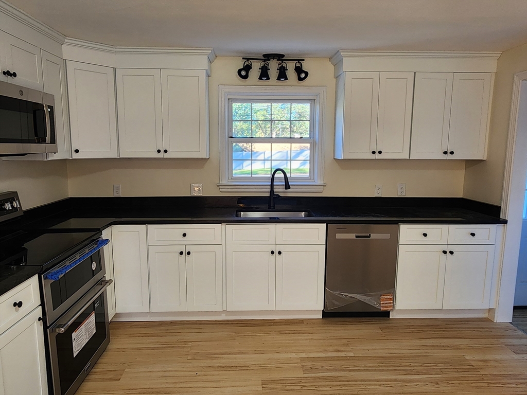 236 Pondview Drive Springfield, MA 01118 - Photo 14 of 23 a kitchen with granite countertop white cabinets white stainless steel appliances a sink and a window