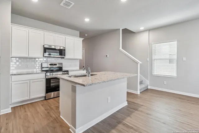 a kitchen with stainless steel appliances granite countertop a stove a sink and a refrigerator