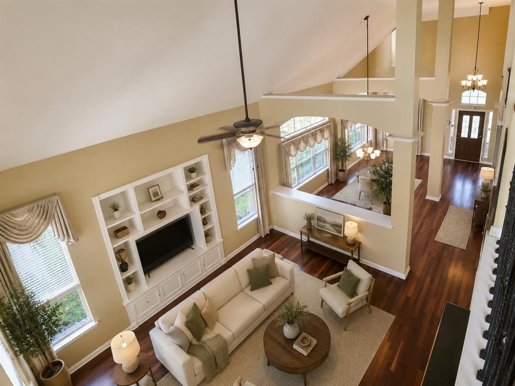 5708 Rickshaw Lane Plano, TX 75094 - Photo 20 of 28 Two-story living area featuring a vaulted ceiling with a ceiling fan, a built-in media center with shelving, and wood-finish flooring