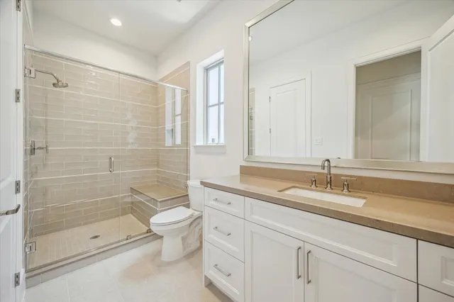 a bathroom with a granite countertop sink a toilet and shower