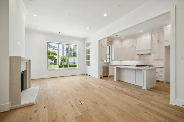 a large kitchen with a refrigerator a sink dishwasher stove and white cabinets with wooden floor