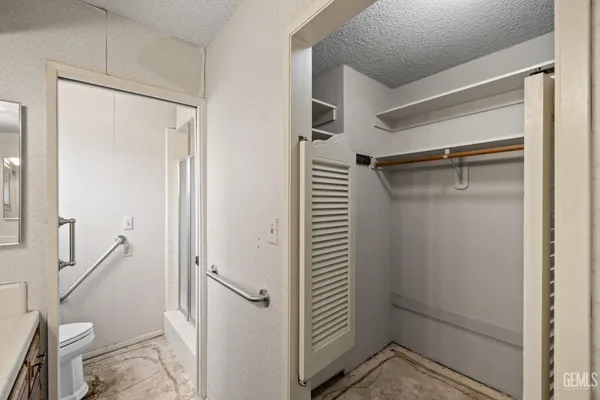 an empty room with a chandelier fan and windows