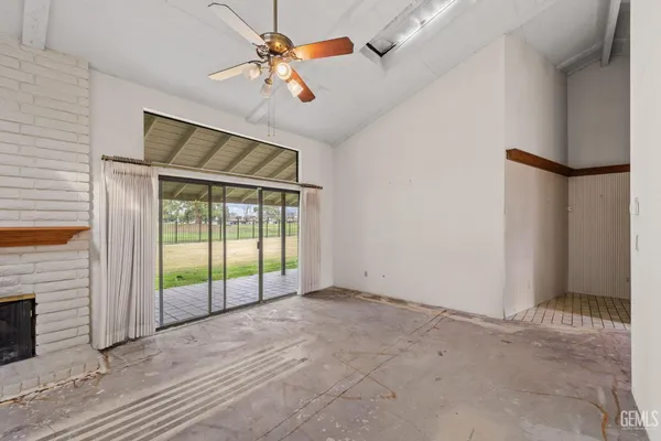 an empty room with chandelier fan and windows