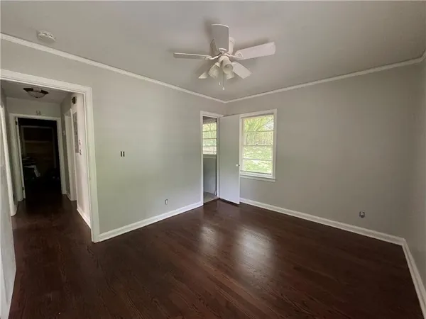 an empty room with wooden floor closet and windows