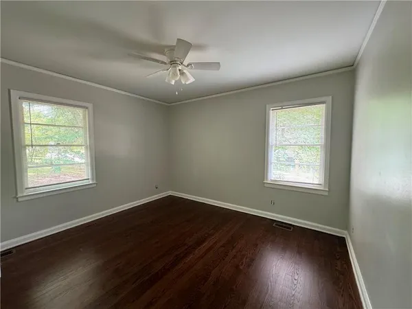 a view of an empty room with wooden floor and a window