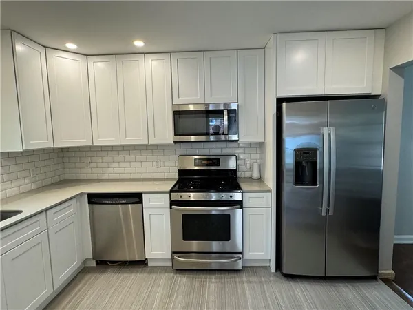 a kitchen with white cabinets and stainless steel appliances