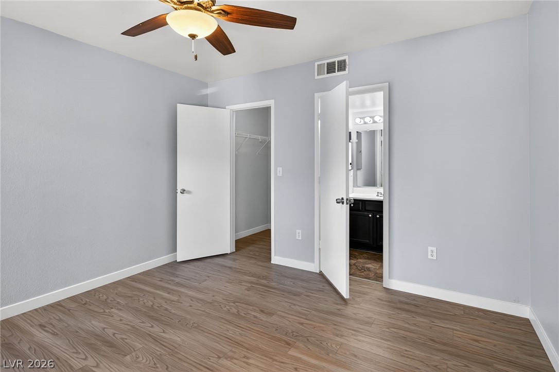 7255 West Sunset Road, Unit 2144 Las Vegas, NV 89113 - Photo 7 of 23 Unfurnished bedroom with wood finished floors, a spacious closet, ensuite bathroom, and a ceiling fan