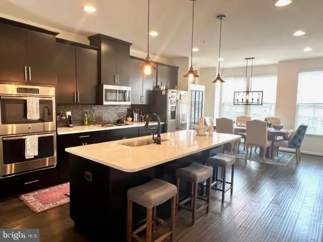 a kitchen with stainless steel appliances kitchen island granite countertop a kitchen island hardwood floor sink stove dining table and chairs