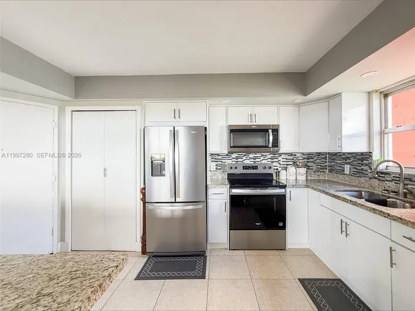 a kitchen with a refrigerator sink and cabinets