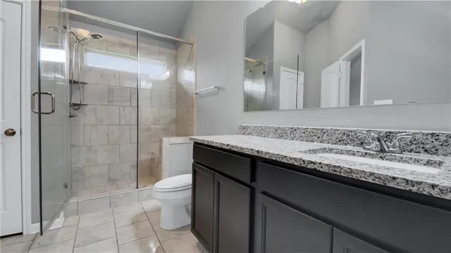 a bathroom with a granite countertop sink a toilet and shower