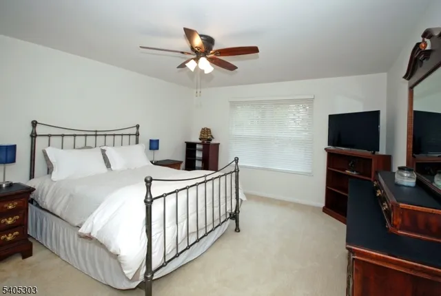 a bedroom with a bed and a flat tv screen on the dresser