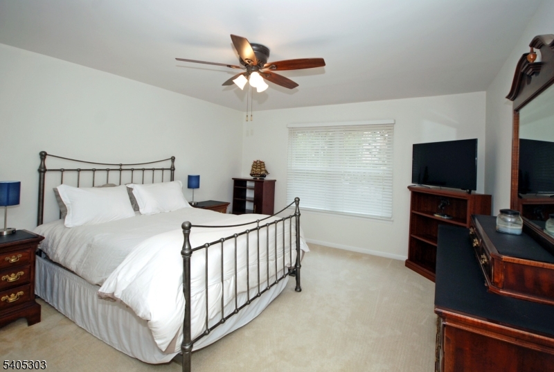 10 Apache Way Somerville, NJ 08876 - Photo 21 of 37 a bedroom with a bed and a flat tv screen on the dresser