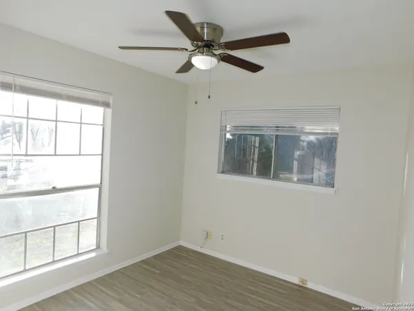 an empty room with wooden floor closet and windows