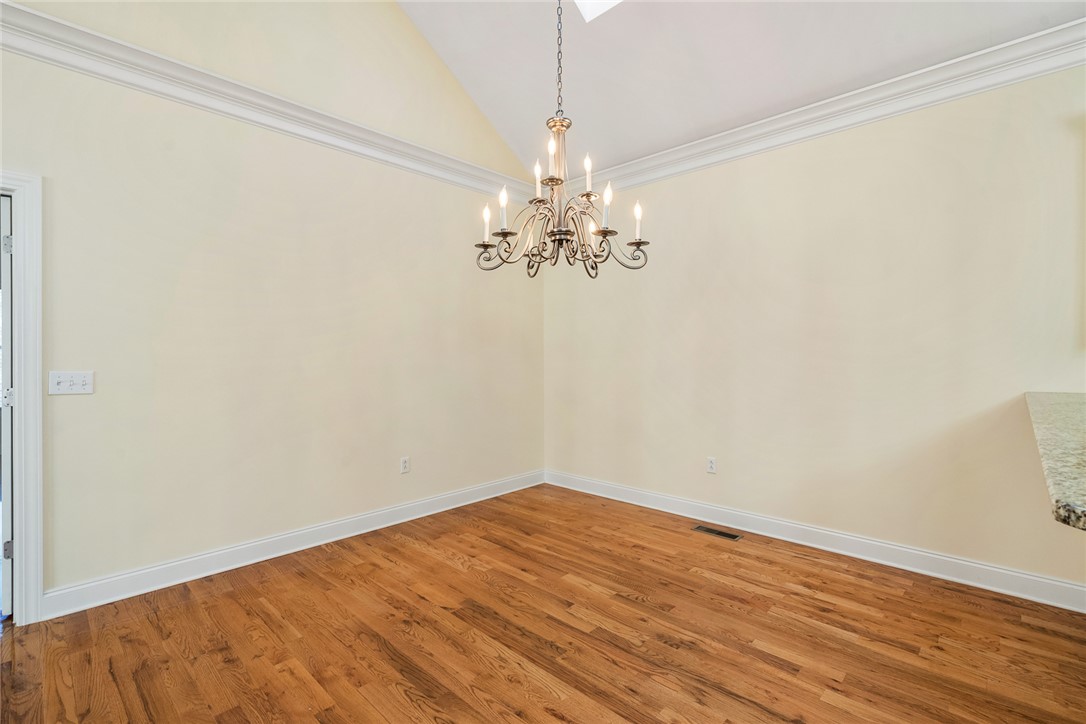 16 Oleander Drive Anderson, SC 29621 - Photo 11 of 37 Elegant hardwood flooring grounds a room featuring crown molding and a classic chandelier.